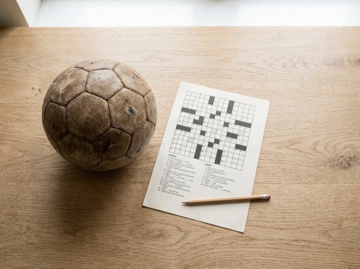 Ein Fußball liegt neben einem gedruckten Kreuzworträtsel
